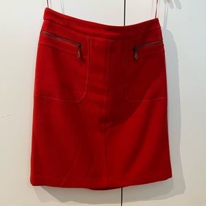 Red wool skirt with brown leather details at zipper pockets.